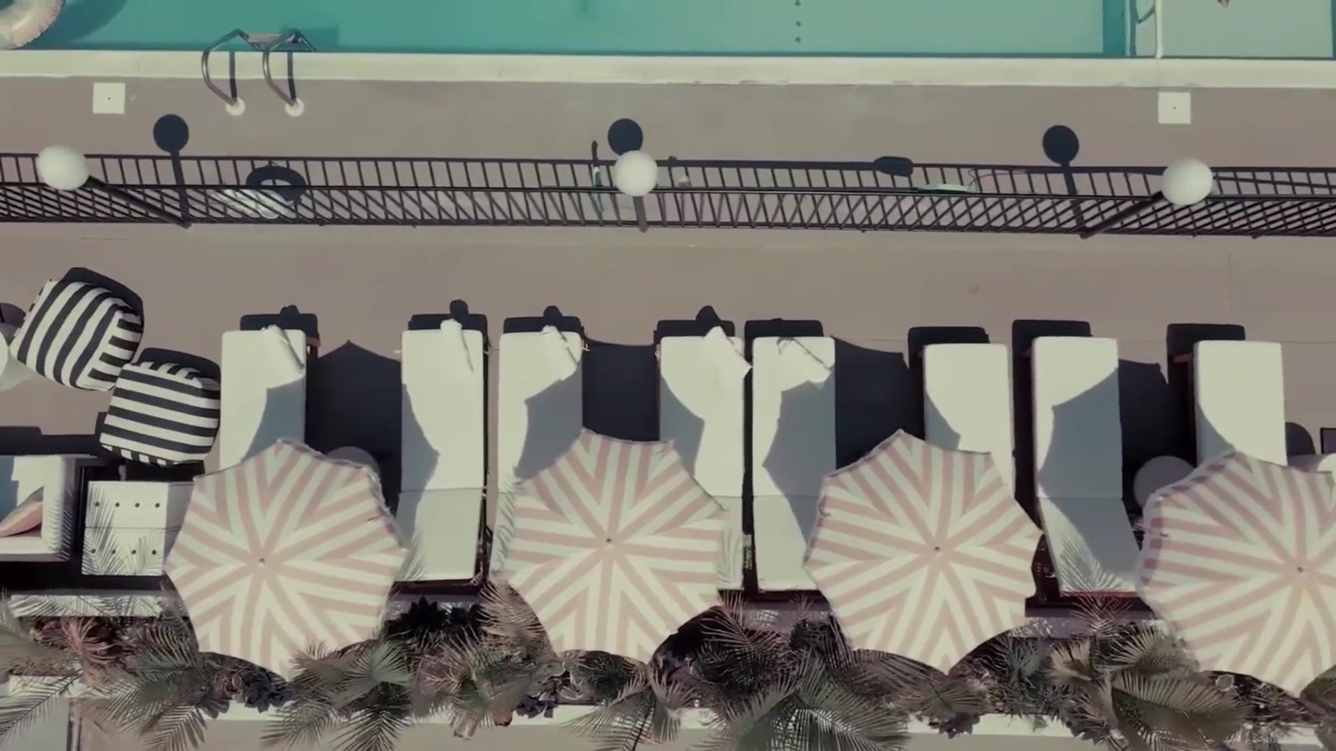 Aerial view of The Shore House pool with pink striped umbrellas and lounge area