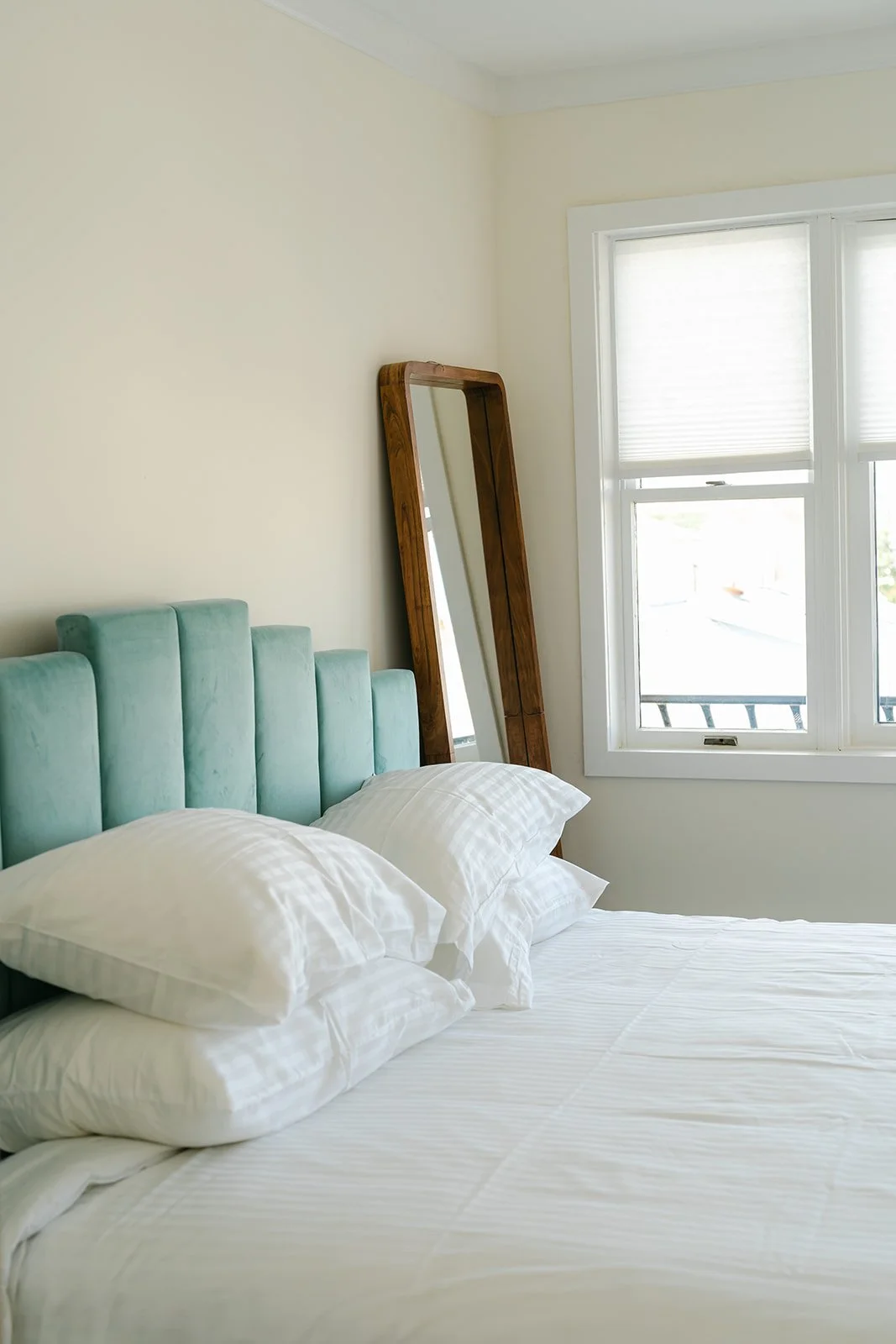 King room with teal velvet headboard and coastal decor